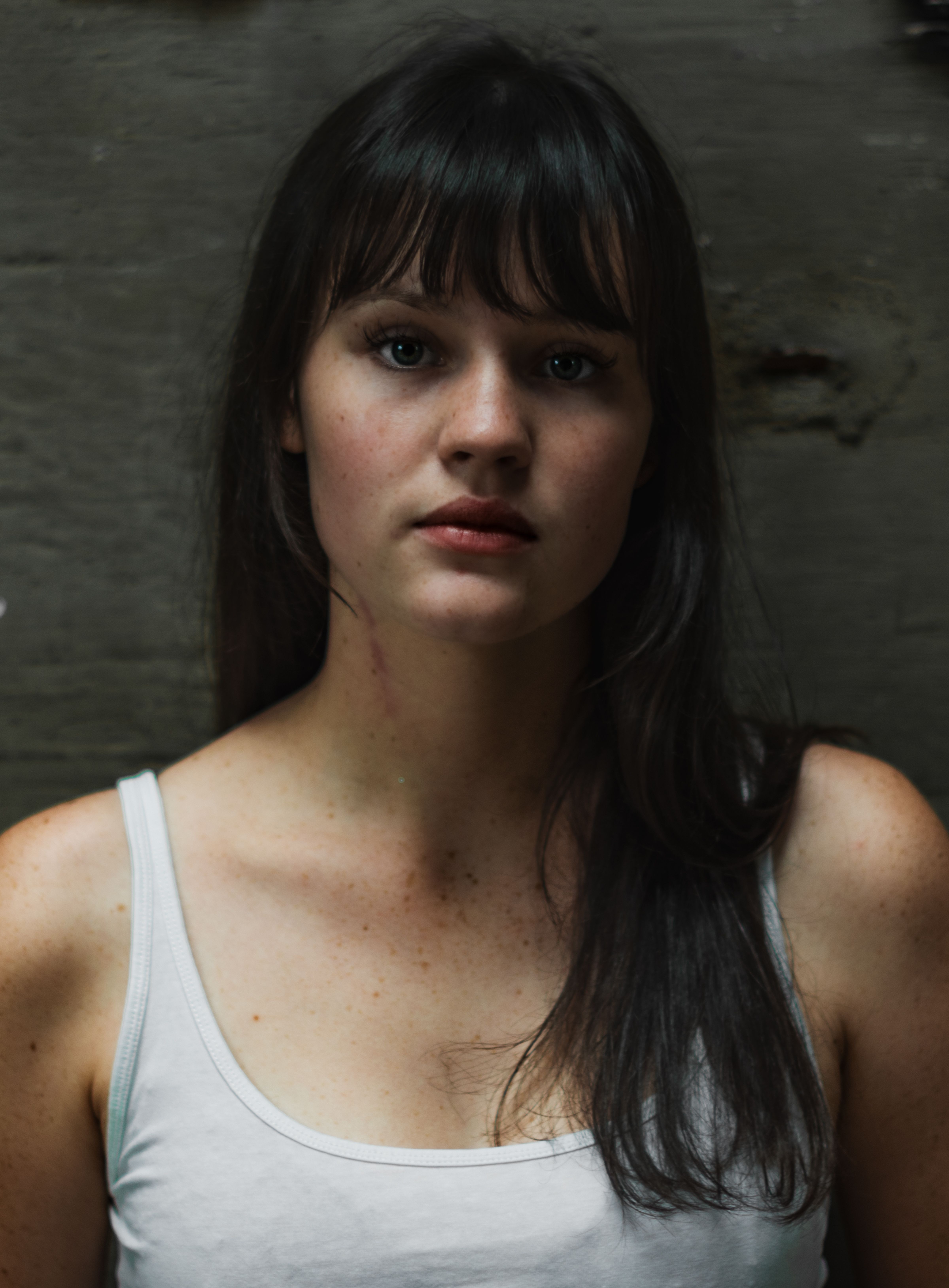 Close-up portrait of a young woman with bangs wearing a tank top in Kassel, Germany.