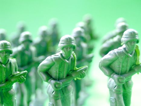 Array of green toy soldiers in a battle formation on a blurred background.