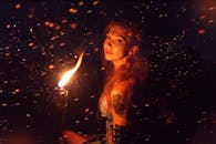 一个女人手持火炬，站在繁星点点的夜空下，构成了一幅神秘的肖像