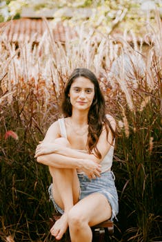 A young woman sitting barefoot in a field, embracing nature and enjoying the warmth of summer.