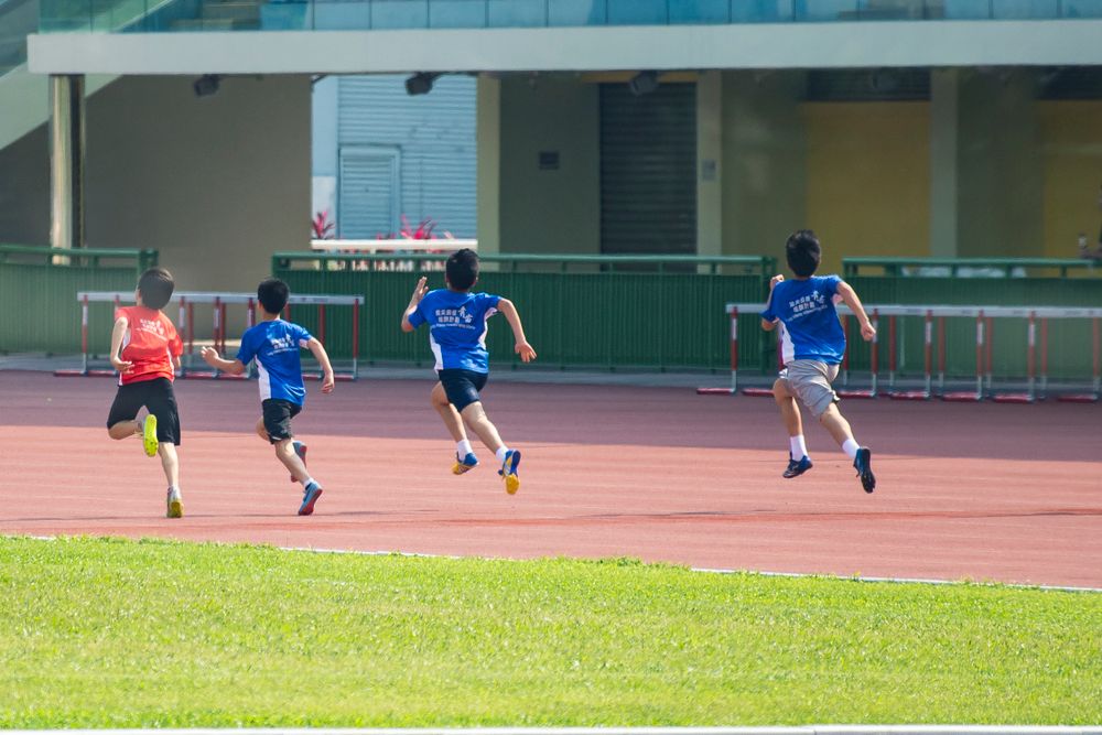 Boys racing on a running track on a sunny day
