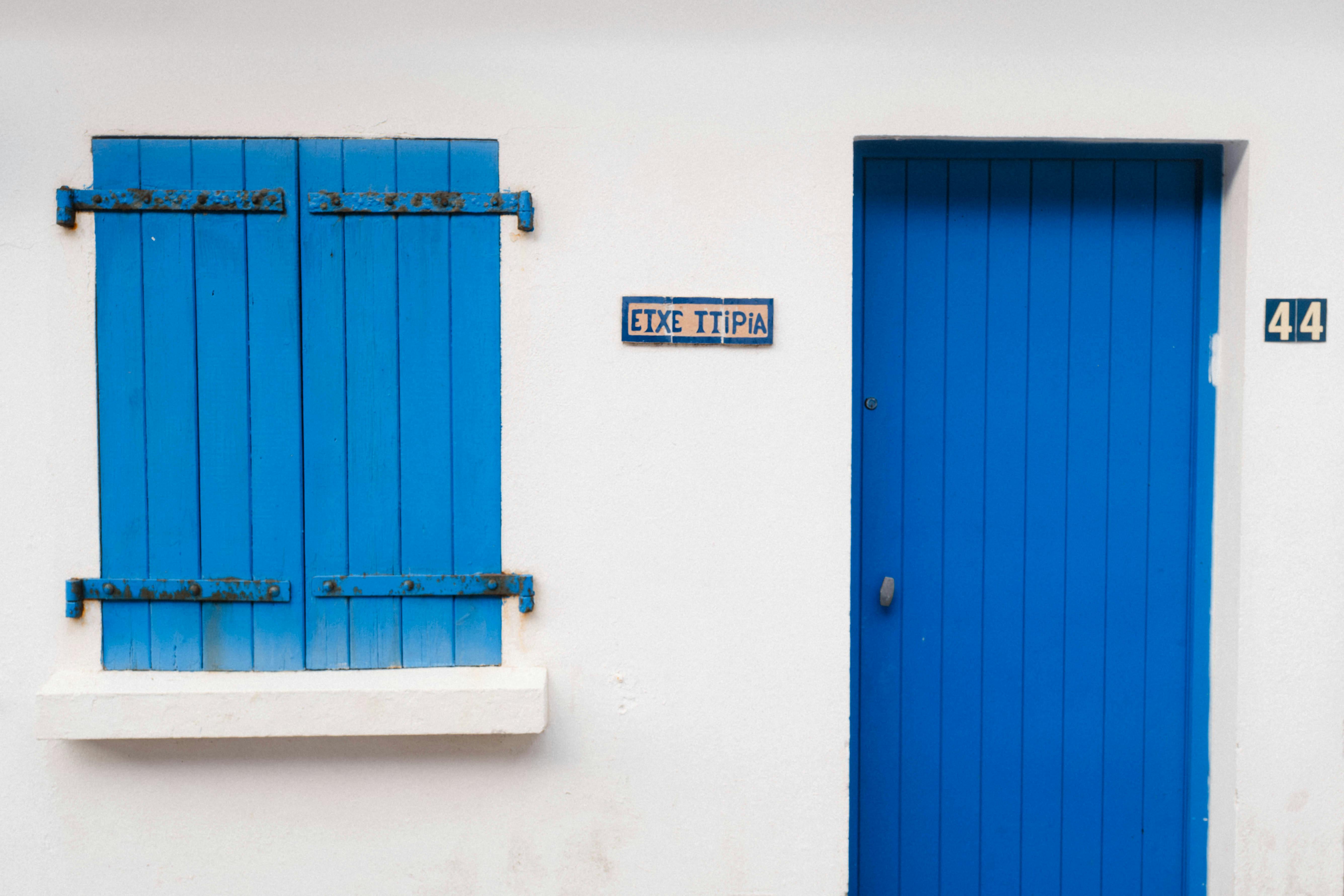 Rustic blue door and shutters on a white house in Biarritz, France.
