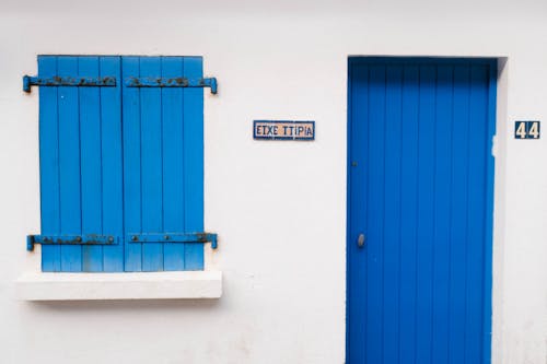 A blue door and blue shutters on a white building