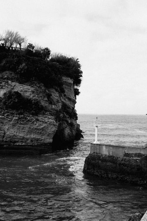 A black and white photo of a lighthouse near the ocean