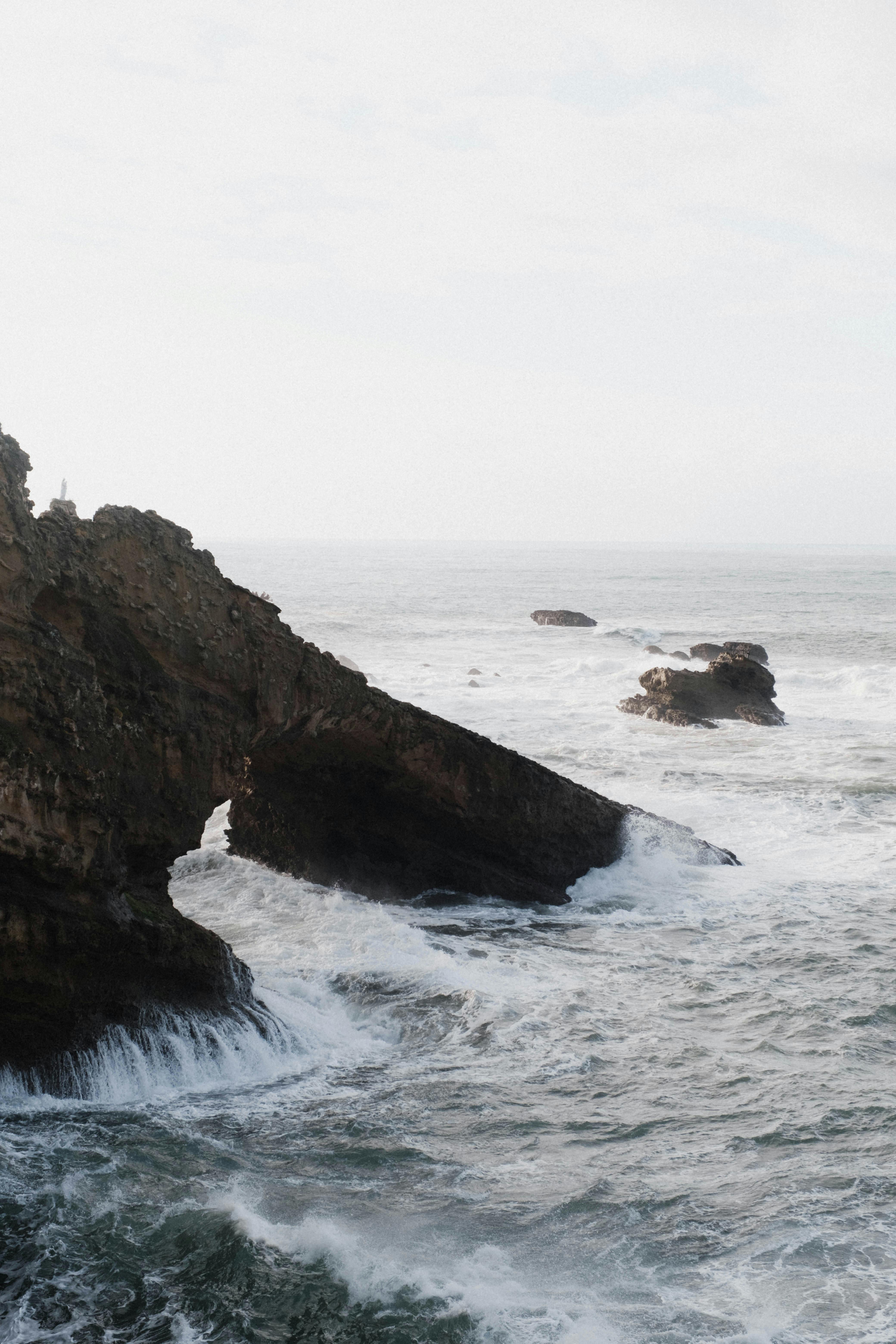 Breathtaking ocean view with natural rock arch in Biarritz, France with waves crashing.