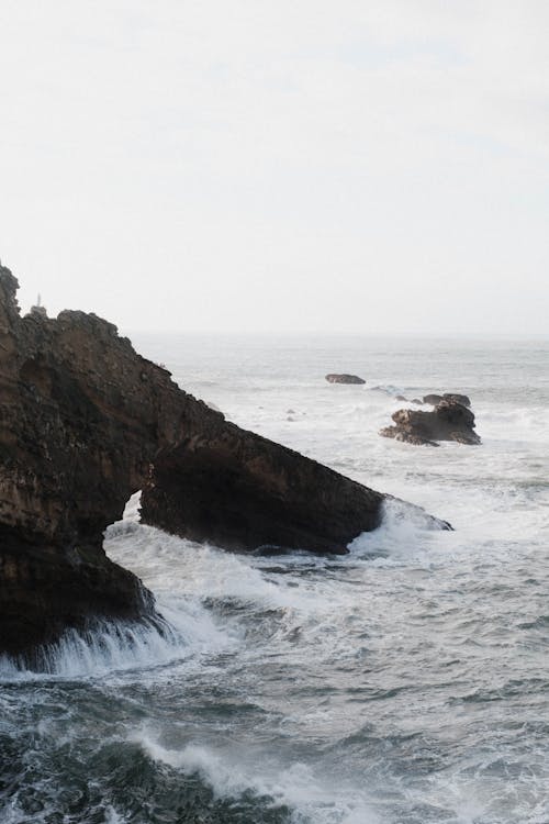 A rock formation in the ocean with waves crashing