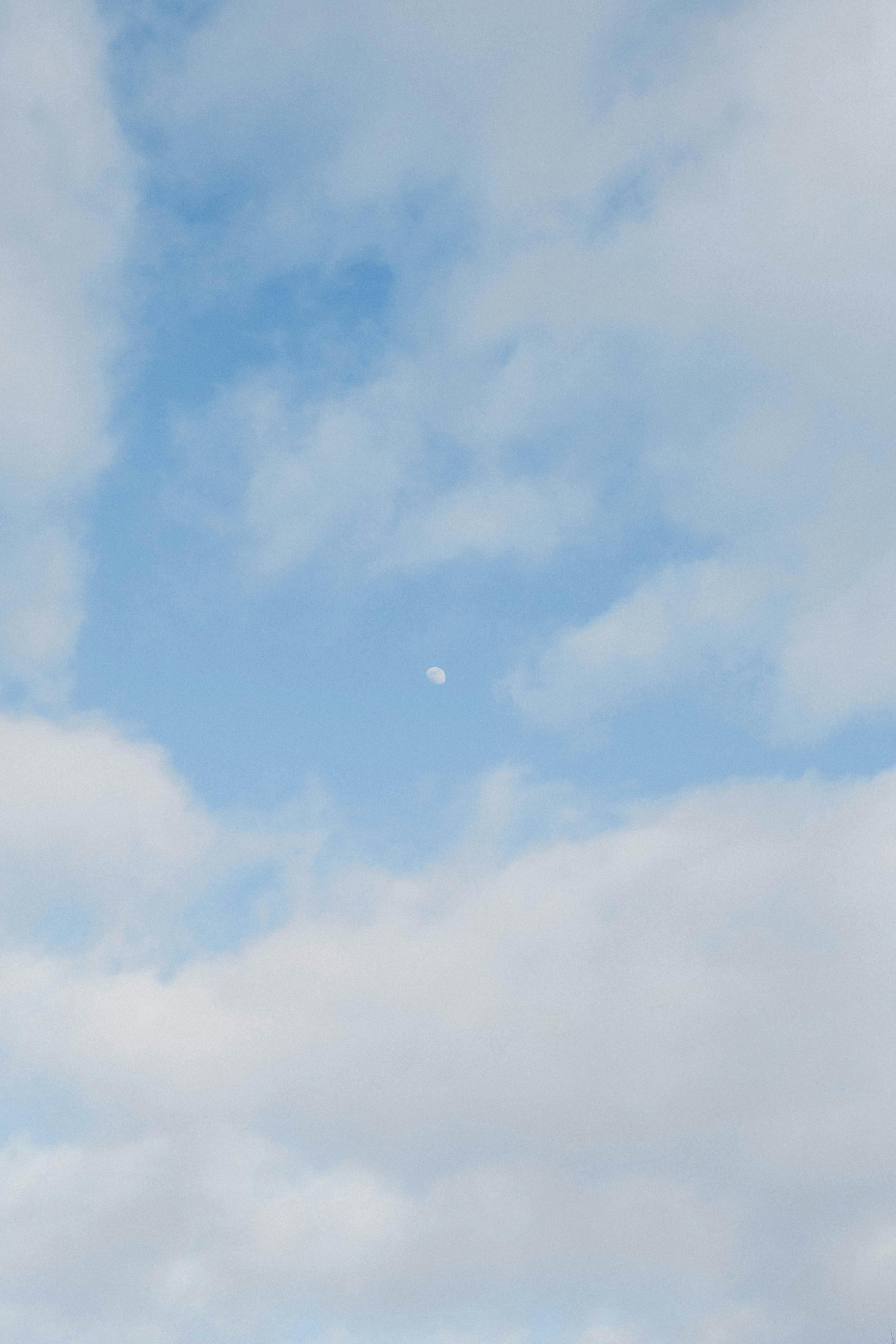 Serene blue sky with floating clouds and visible moon over Biarritz, France.