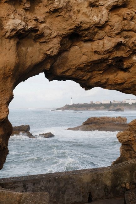 Stunning view through a rock arch of Biarritz's rugged coastline and ocean waves.