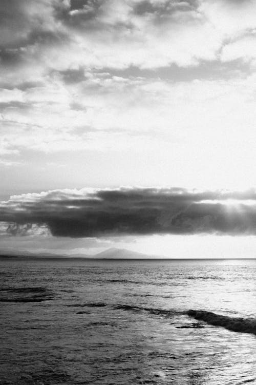 Black and white photo of the ocean with clouds