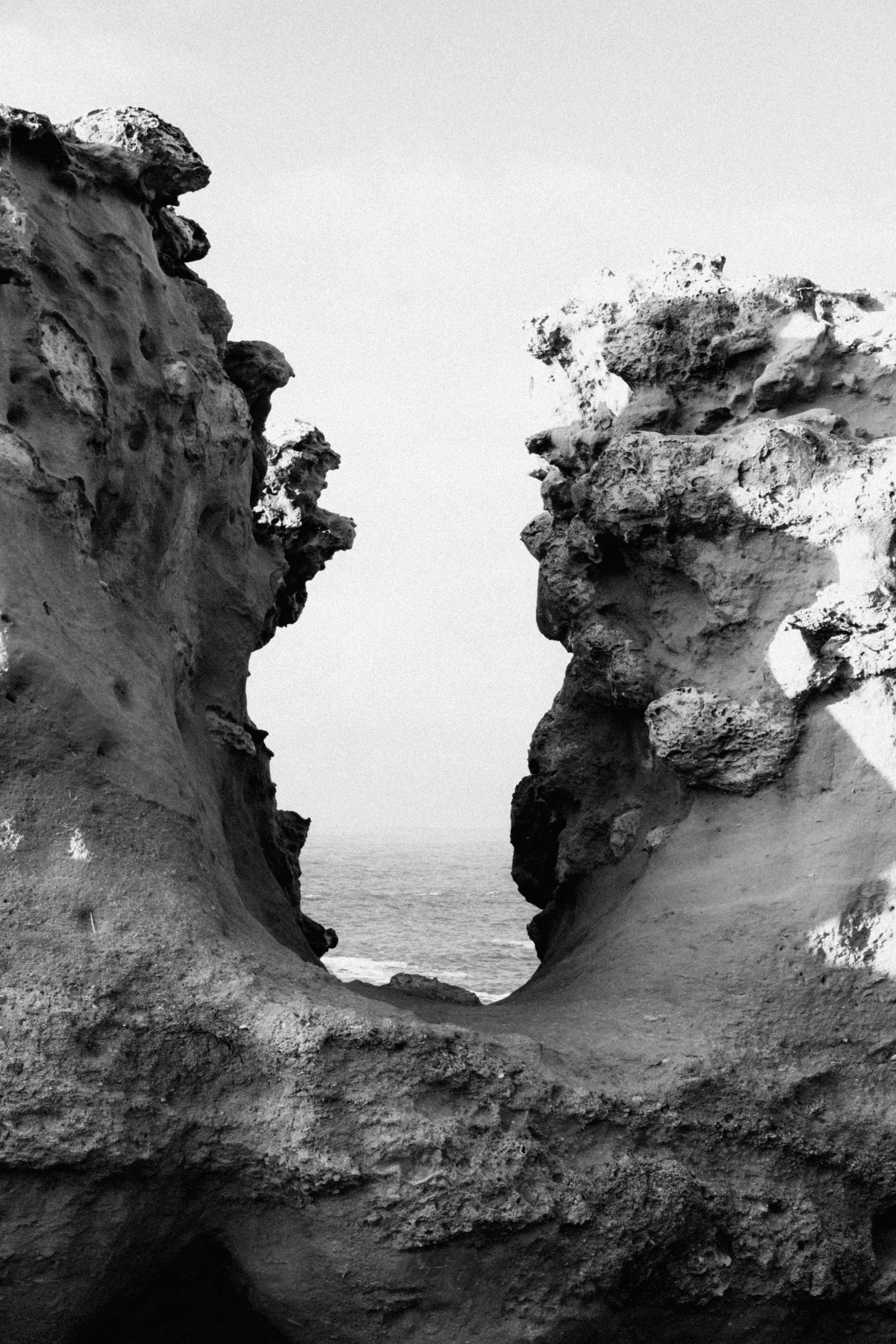 Dramatic black and white image of eroded rock formations by the sea in Biarritz, France.