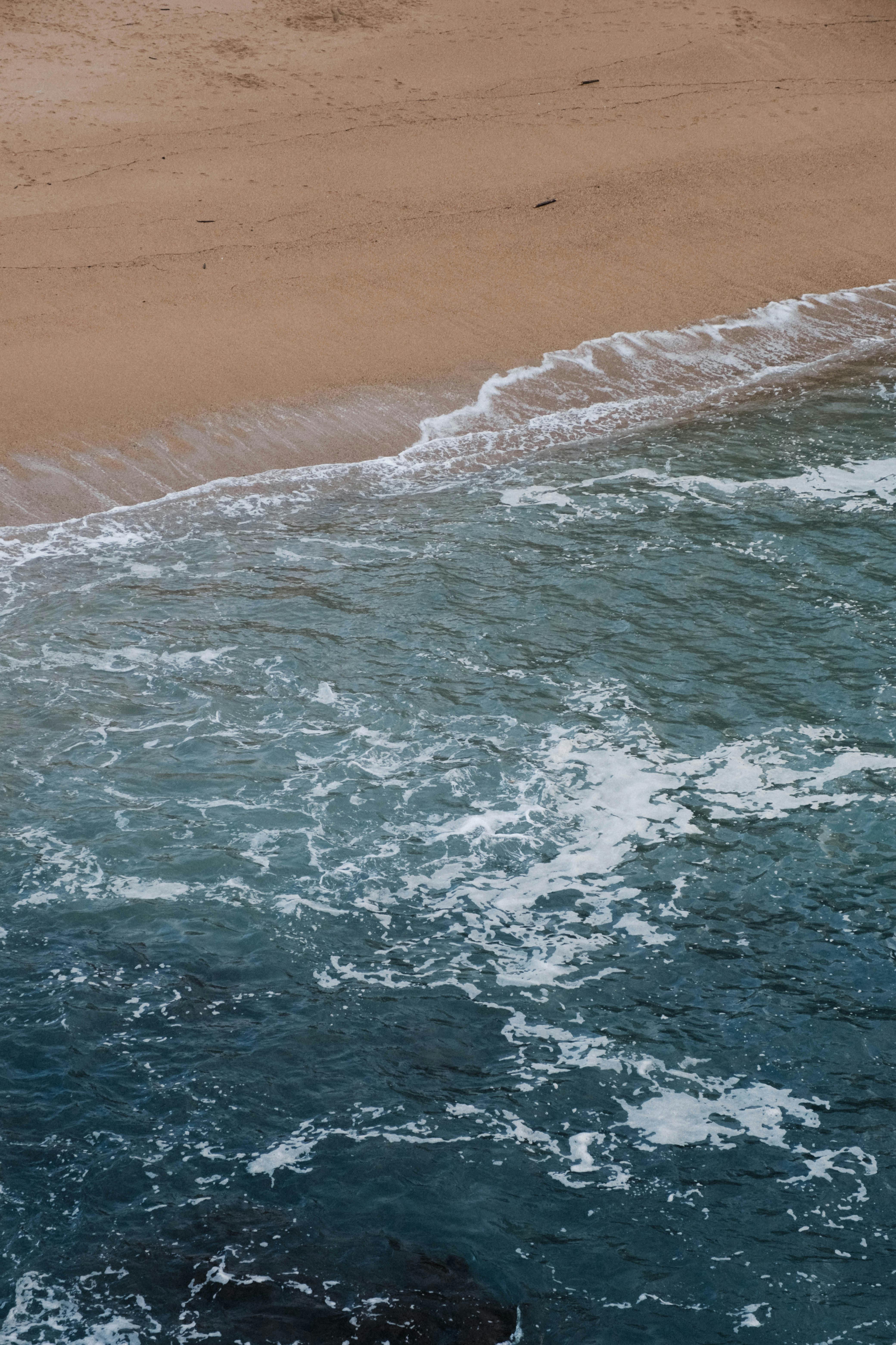 A stunning aerial view of ocean waves hitting the sandy shore in Biarritz, France.