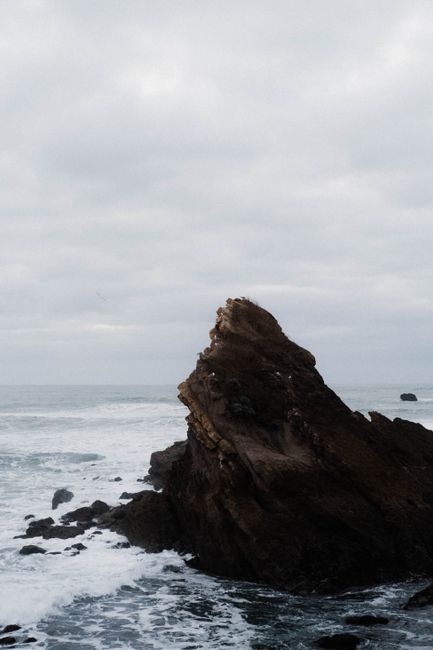 Moody seascape featuring a striking rock formation against the Biarritz ocean under an overcast sky.