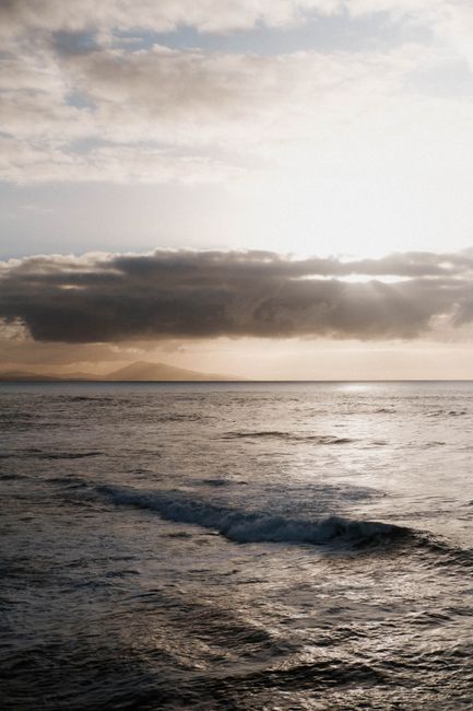 Calm Atlantic waves and a dramatic sunset sky in Biarritz, France create a serene coastal view.