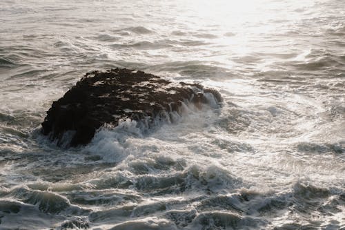 A rock in the ocean with waves crashing on it
