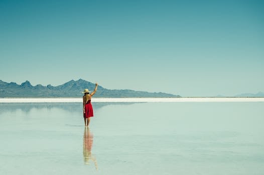一名身穿红色连衣裙的女子，站在宁静的盐滩上，以山脉为背景，享受着孤独与反思