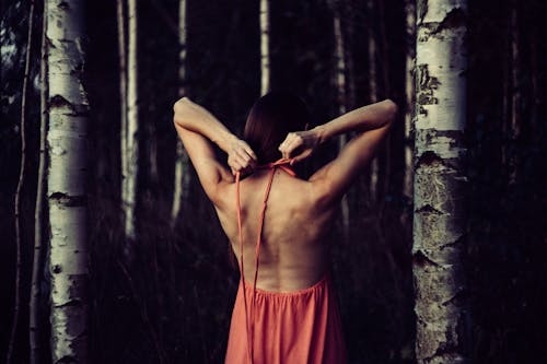 Woman Wearing Pink Halter Dress Standing Beside Grey Trees