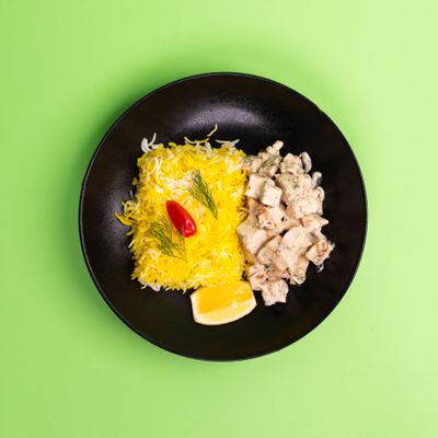 Saffron rice and herbed chicken on a dark plate, photo by Ali Dashti on Pexels