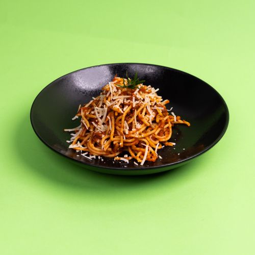 Free A mouth-watering plate of spaghetti with tomato sauce and cheese on a green background. Stock Photo