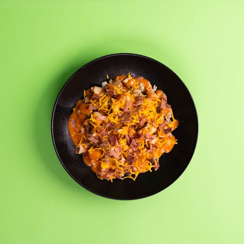 A black plate with a bowl of food on top