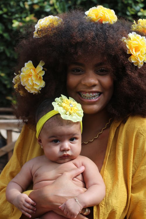 grátis Mulher Com Um Vestido Amarelo Segurando Um Bebê Foto profissional
