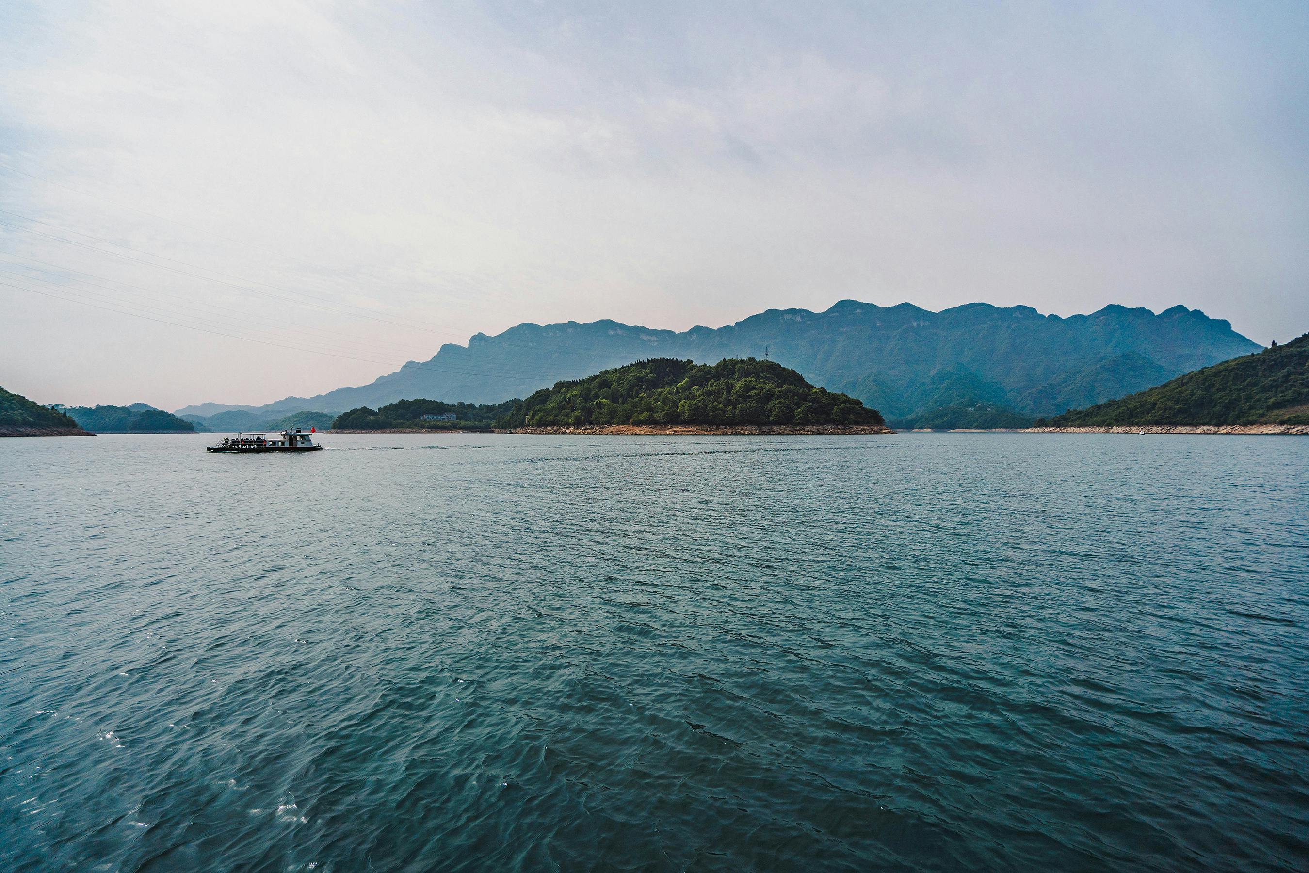 Breathtaking view of a tranquil lake with mountain backdrop in Hubei, China, ideal for travel enthusiasts.
