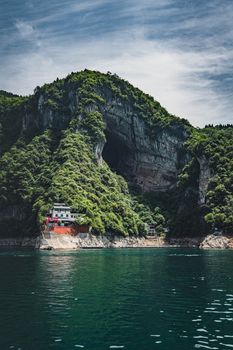 中国西昌的悬崖令人惊叹，绿树成荫，水边坐落着房屋