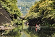 在中国西昌，一个人正在绿树成荫、风景优美的河上划船