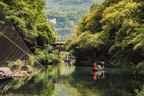Free A person rows a traditional boat on a scenic river surrounded by lush greenery in Yichang, China. Stock Photo