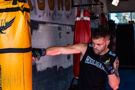 Focused male boxer practicing punches on a heavy bag in the gym.