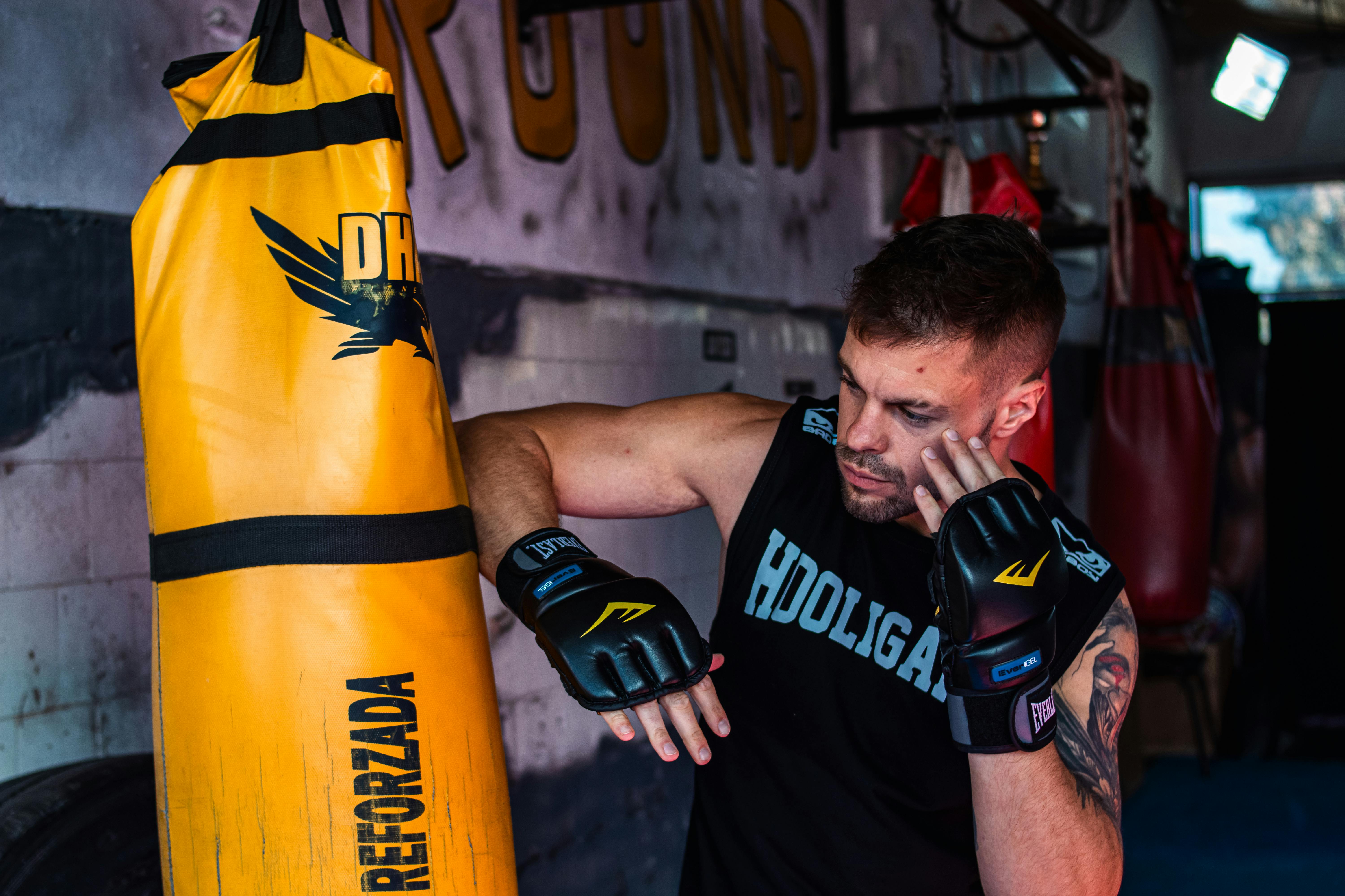 Young male boxer practicing strikes on a punching bag in the gym.