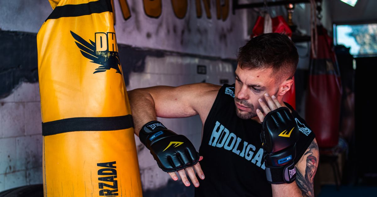 Young male boxer practicing strikes on a punching bag in the gym.