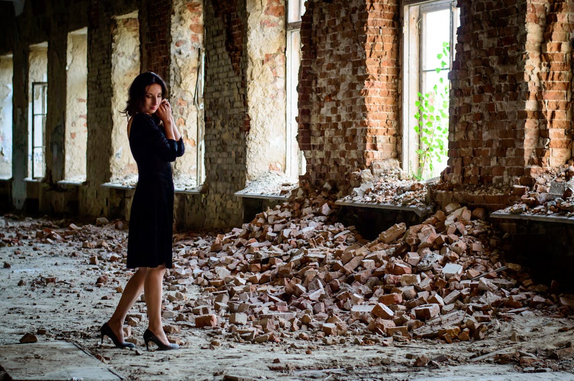Free Woman in Black Dress Standing in Front of Pile of Bricks Stock Photo