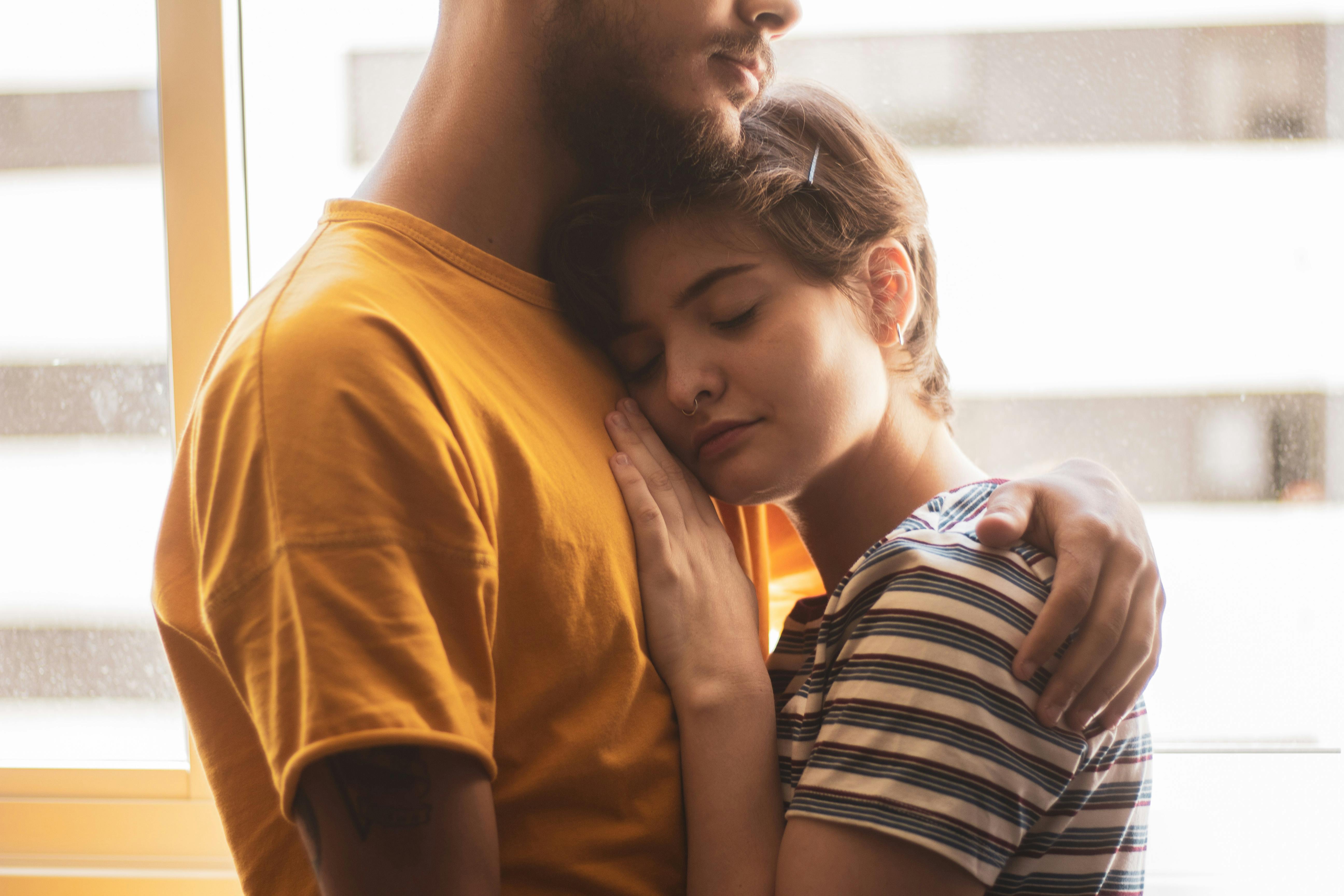 Man Wearing Yellow Shirt Holding Woman Wearing White and Blue Stripe Shirt