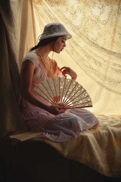 Photo of Woman Sitting While Holding Her Fan