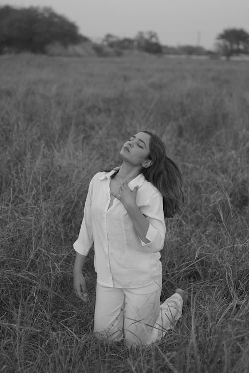 Black and White Photo of a Young Woman Kneeling on a Field 