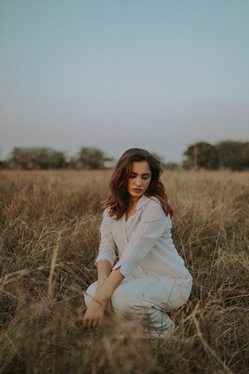 Young Woman in a White Outfit Posing on a Field 