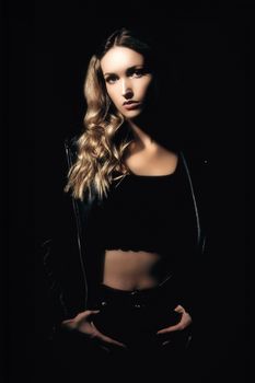 Studio shot of a woman posing in a leather jacket with dramatic lighting.
