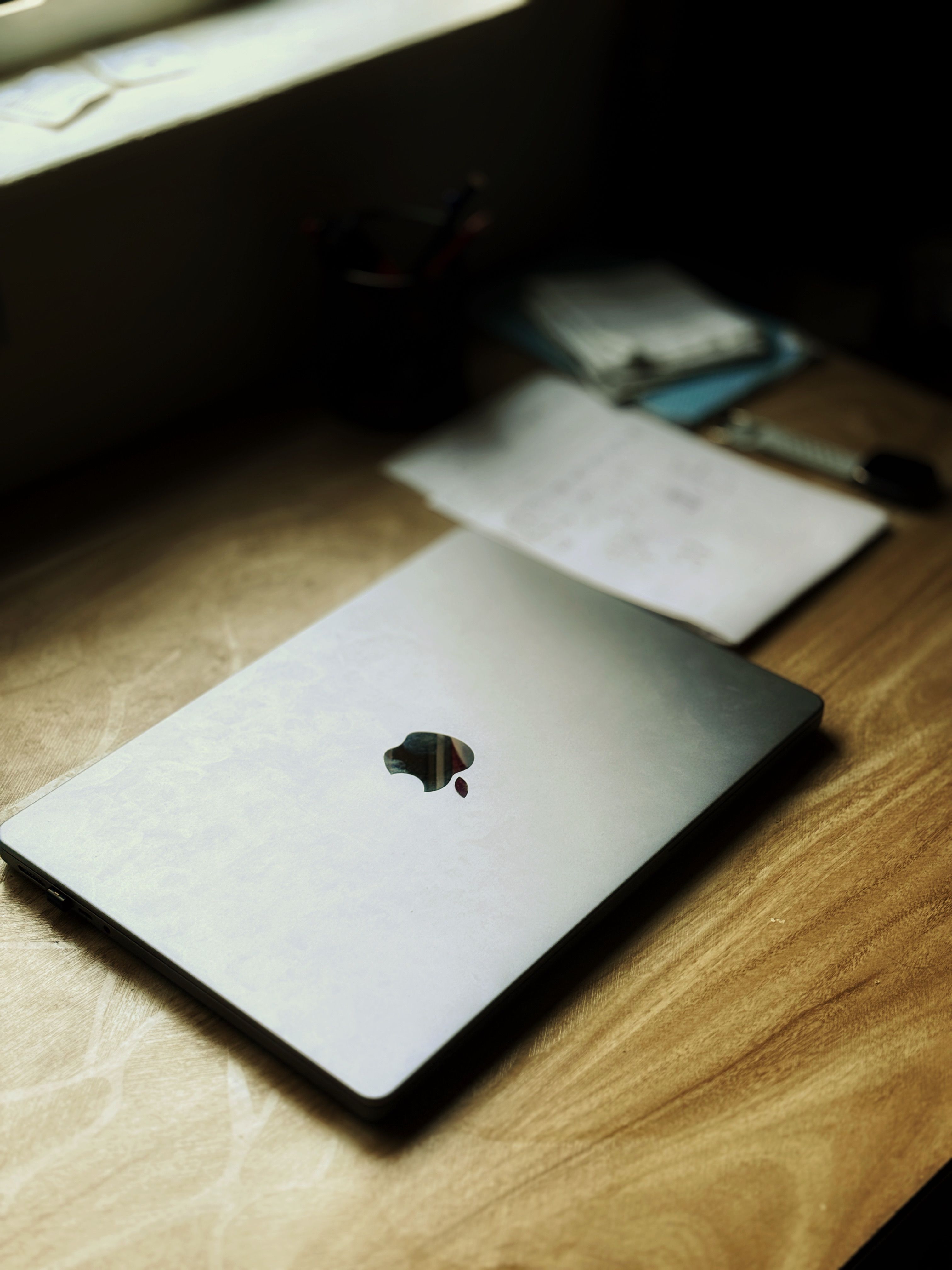 A closed laptop on a wooden table by the window