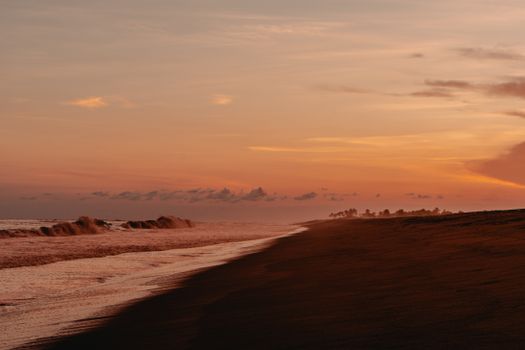 A serene beach at sunset with a golden sky, waves crashing gently on the shore.