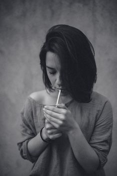 这幅戏剧性的黑白肖像描绘了一名点燃香烟的女子，唤起了情感与深度