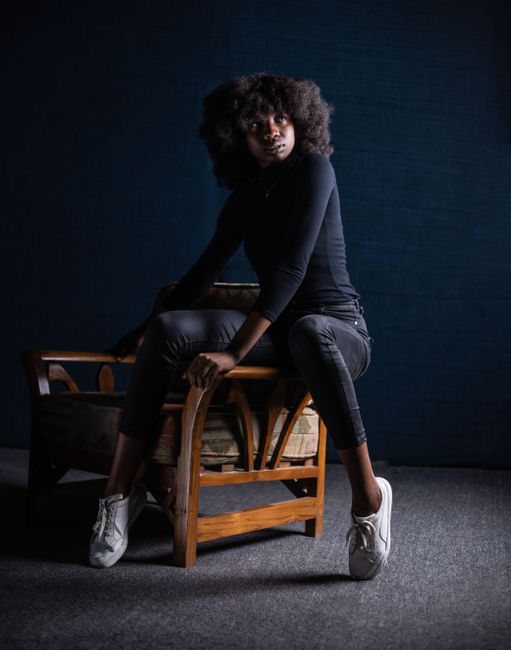 Elegant photoshoot of a woman with afro hair posing in a chic indoor studio setting.