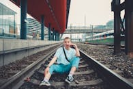 一位年轻女子身着休闲装，充满现代气息地坐在城市铁轨上