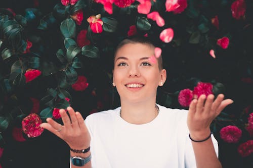 Woman in White Crew-neck Shirt Playing Pink Flowers, Pieces of Jewelry