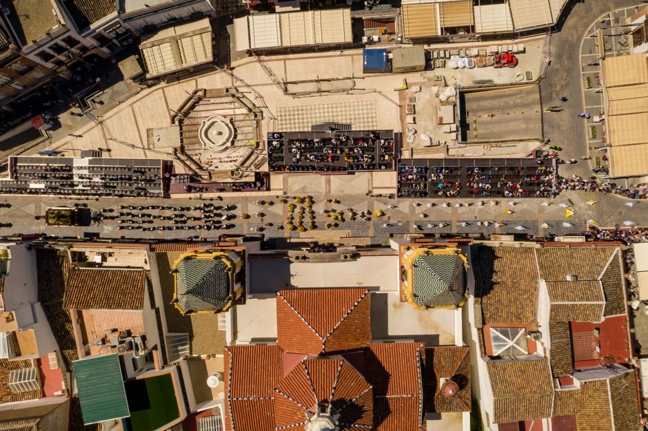 Toma de dron de una escena festiva en la calle en Ronda, España, mostrando arquitectura y grandes multitudes.