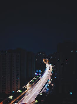 广州市夜间鸟瞰图中，高速公路上车辆的灯光痕迹清晰可见