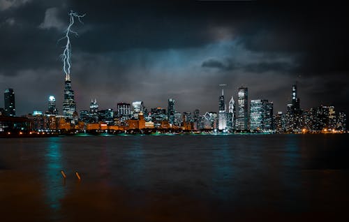 Photo of Chicago Cityscape at Night While Lightning Strikes High Rise Building