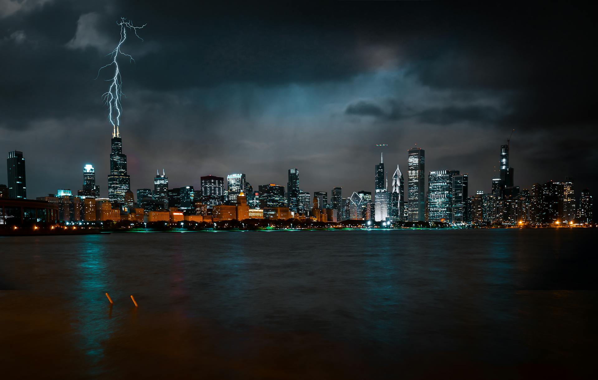 Photo of Chicago Cityscape at Night While Lightning Strikes High Rise Building