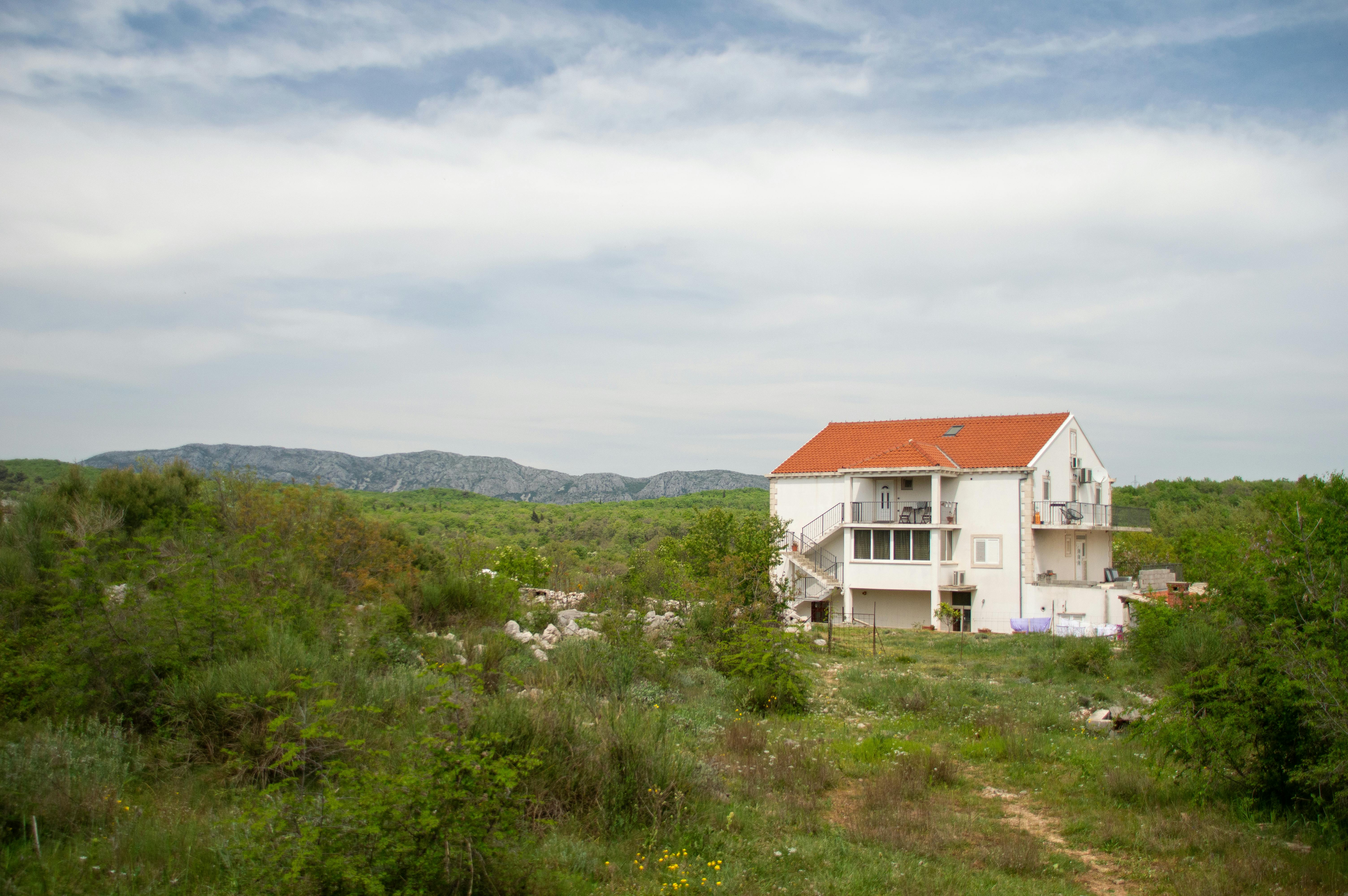 Serene countryside landscape with a house surrounded by greenery and mountains in Croatia.