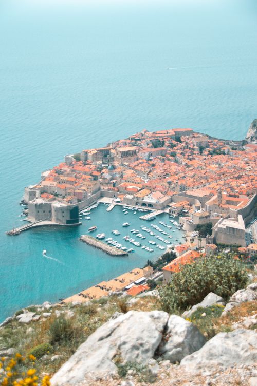 Free Stunning aerial shot of Dubrovnik's historic harbor with clear blue waters and iconic city walls. Stock Photo