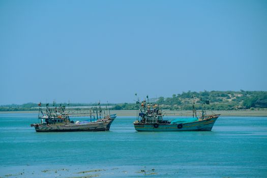 Fishing boats on the serene Arabian Sea near Dwarka, Gujarat, India under clear blue skies.